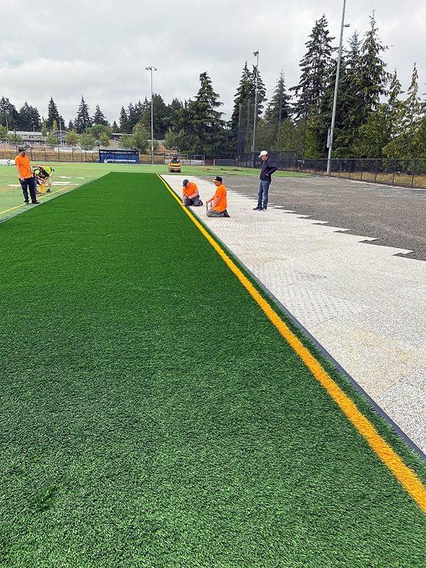 People in orange shirts working on a green field