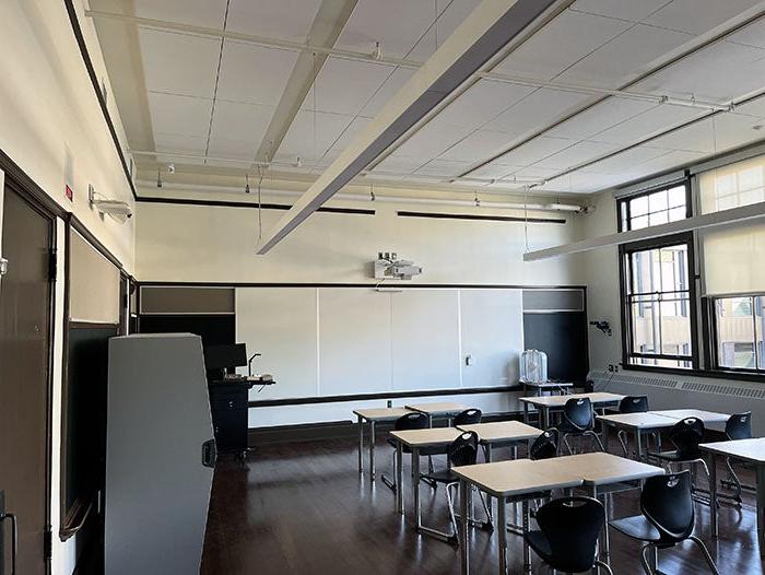 a room with tables and chairs and a white board