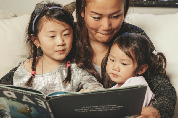 Parent reading a book to students