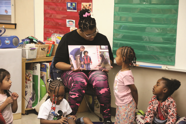 Preschool teacher readnig a book to students